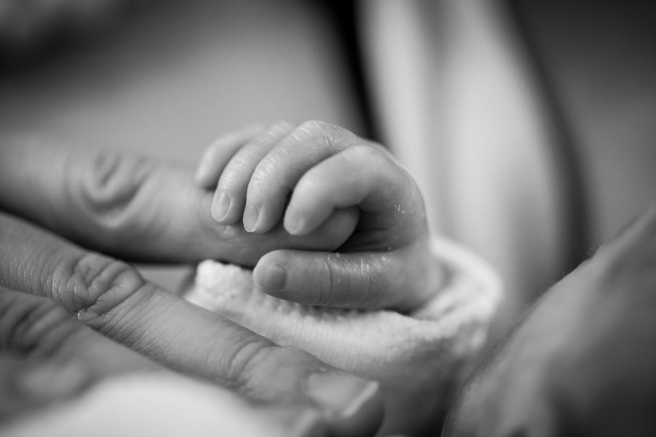 infant hand grabbing adult finger