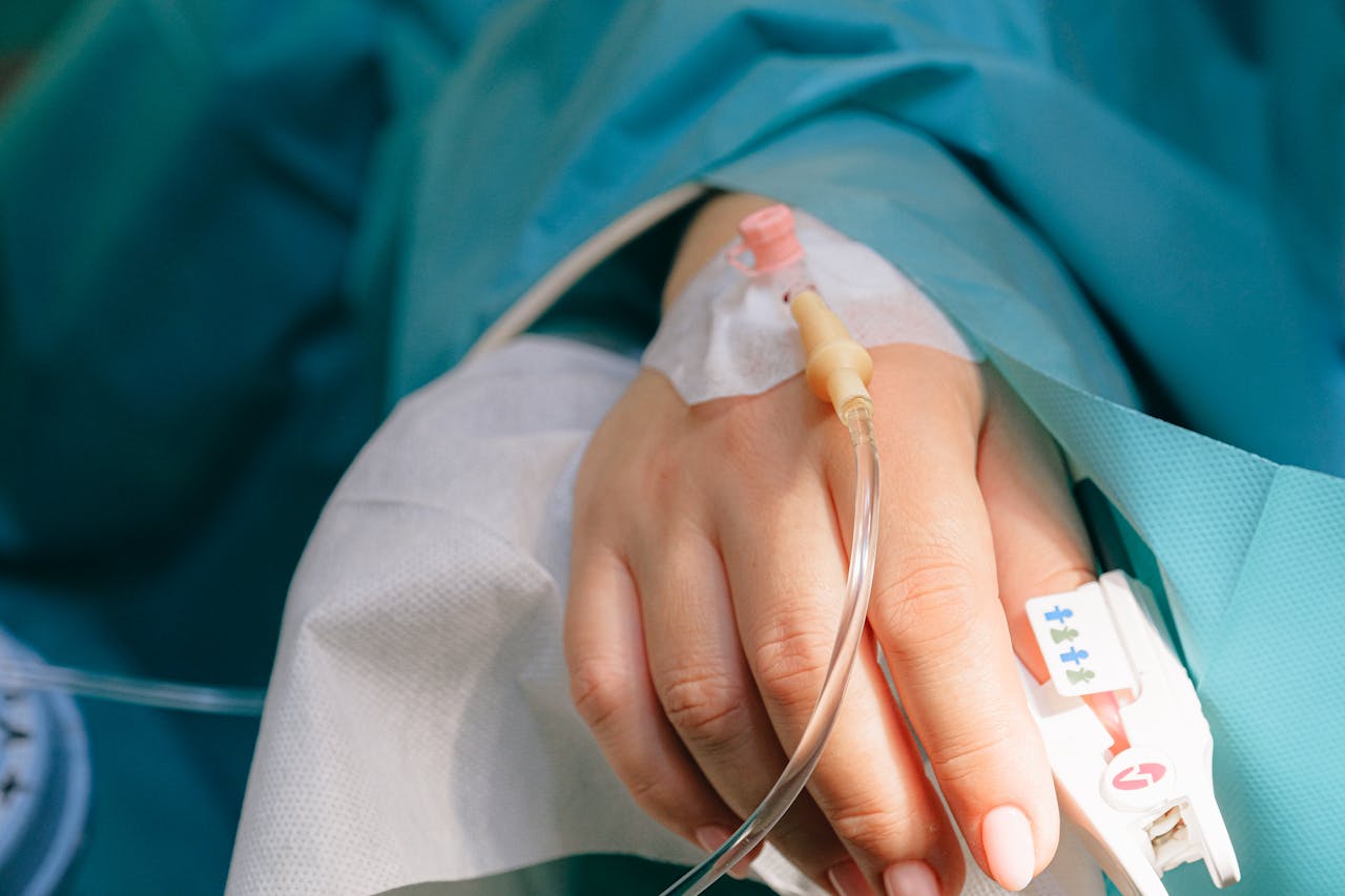 Hand with IV in hospital bed.