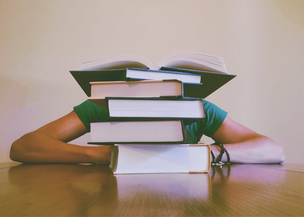 College student behind a stack of books.